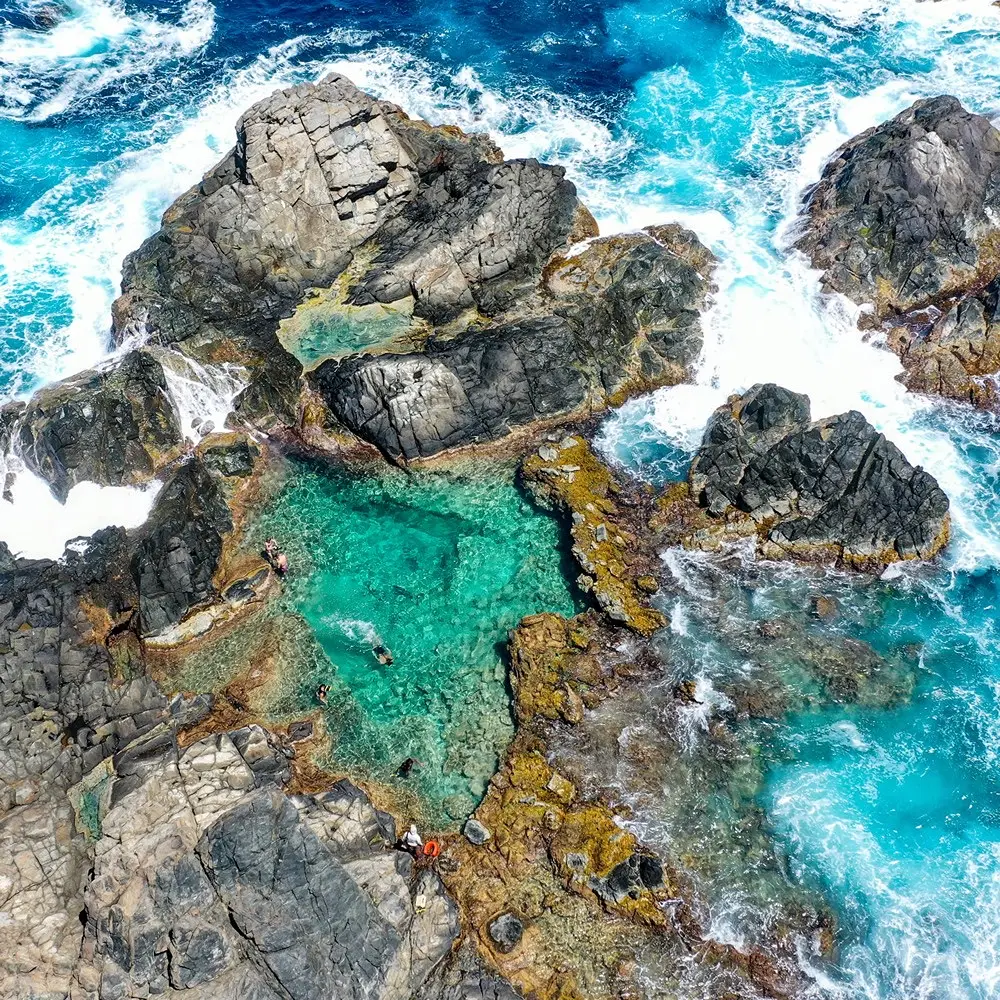 Aerial drone shot of the Natural Pool surrounded by volcanic rocks